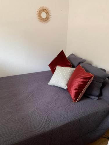 a bed with red and white pillows on it at Appartement vue mer in Sète