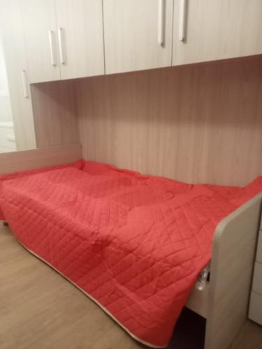 a bed with a red comforter in a room at Nonno Ludovico in Roccasicura