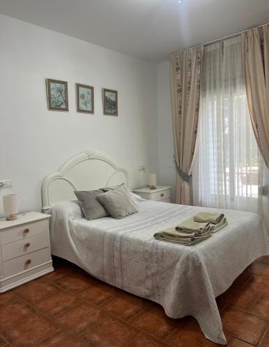 a white bedroom with a large bed and a window at Huerta La Niña Arenas in Órgiva
