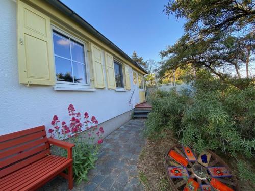 a red bench sitting outside of a house at Uns Gartenhus mit Blick auf das Meer in Thiessow