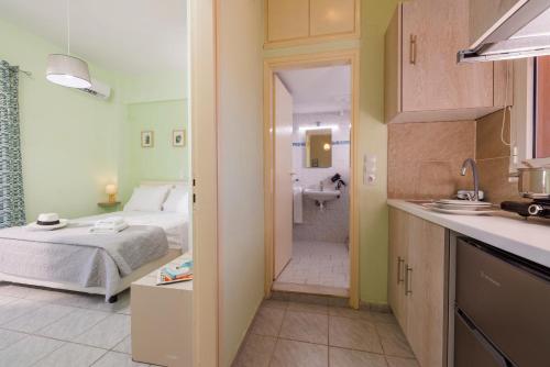 a bedroom with a bed and a bathroom with a sink at Ariadne Apartments in Kato Gouves