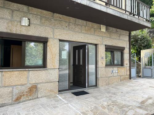a stone house with a black door and windows at Casa de Casarelhos - "Gerês" - Estúdio piso 0 - Apartamento Piso 1 in Geres