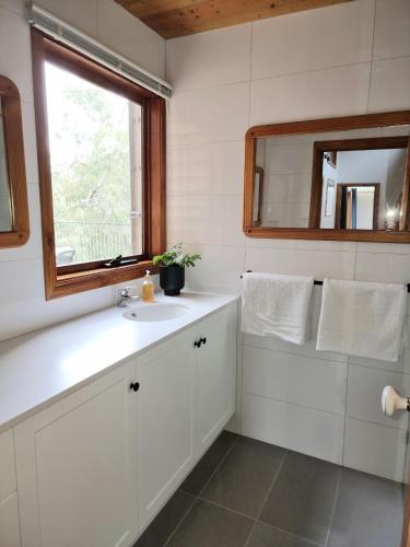 a white bathroom with a sink and a mirror at Queen Room with Balcony - Kookaburra Retreat Homestay in Pakenham