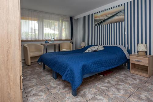 a bedroom with a blue bed and a table and chairs at Dom Wypoczynkowy Anna - opcjonalnie śniadania w Starej Piekarni in Kołobrzeg