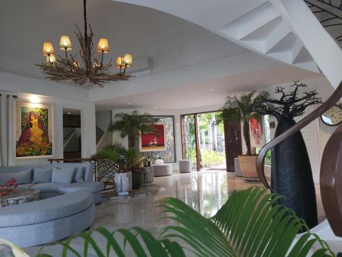 a living room with a couch and a chandelier at La VILLA MAELA GOLF ANAHITA in Beau Champ