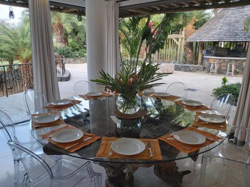 a glass table with plates and a vase with a plant on it at La VILLA MAELA GOLF ANAHITA in Beau Champ