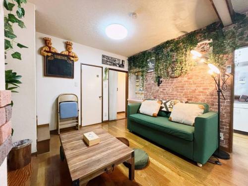 a living room with a green couch and a brick wall at 横浜中央2丁目 in Yokohama