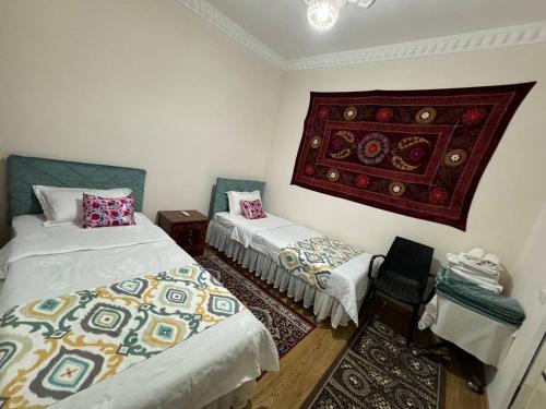 a room with two beds and a chair in it at Boutique Boulevard Bukhara in Bukhara