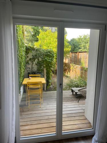 une porte coulissante en verre menant à une terrasse avec une table. dans l'établissement Appartement cosy avec jardin quartier calme, à Toulouse