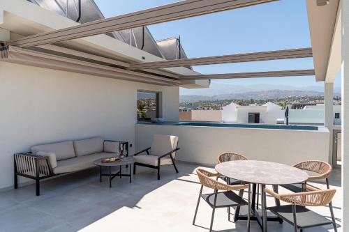 a patio with a table and chairs and a couch at Inea Sole Boutique Hotel in Kato Daratso