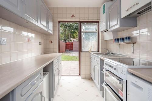 a kitchen with white appliances and a large window at Lovely 4 Bedrooms House Near Romford Station With Parking in Romford