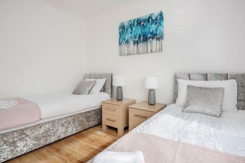 ein Schlafzimmer mit zwei Betten und einem Gemälde an der Wand in der Unterkunft Lovely 4 Bedrooms House Near Romford Station With Parking in Romford