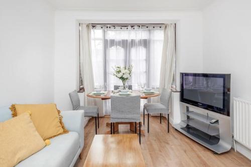a living room with a couch and a table and a tv at Lovely 4 Bedrooms House Near Romford Station With Parking in Romford