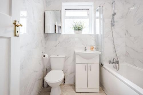 ein weißes Badezimmer mit Toilette und Waschbecken in der Unterkunft Lovely 4 Bedrooms House Near Romford Station With Parking in Romford