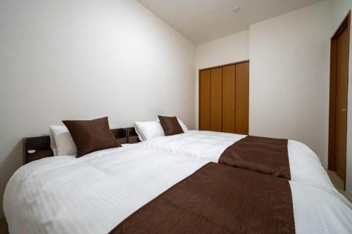 two beds in a bedroom with white and brown at Flex cella satozuka in Ōmagari