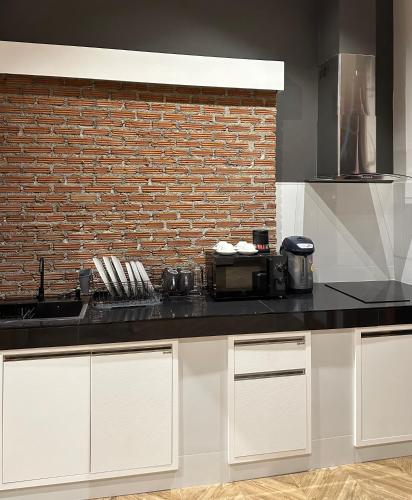 a kitchen with white cabinets and a brick wall at Sabainimman Chiangmai in Ban Choeng Doi Suthep