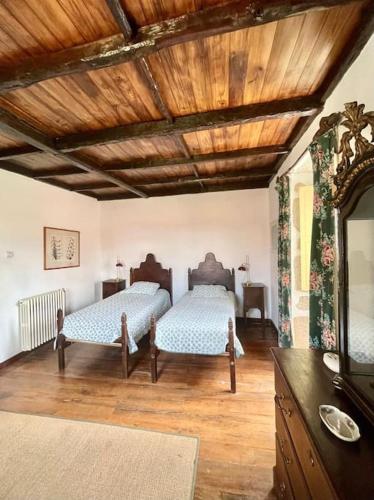 a bedroom with two beds and a wooden ceiling at Quinta de Bóco in Arouca
