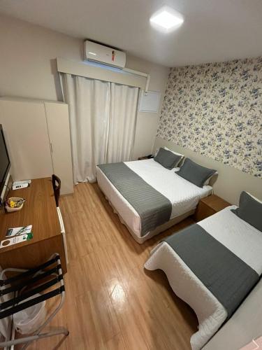 a small room with two beds and a television at Hotel Serra de Jundiaí in Jundiaí