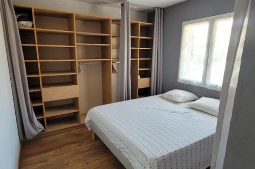 - une chambre avec un lit, des étagères et une fenêtre dans l'établissement Jolie villa 3 faces piscine, à Torreilles