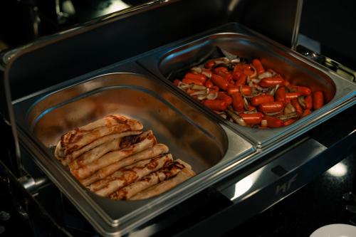 a tray of food with meat and vegetables in an oven at Hotel Tamara Melaka in Melaka