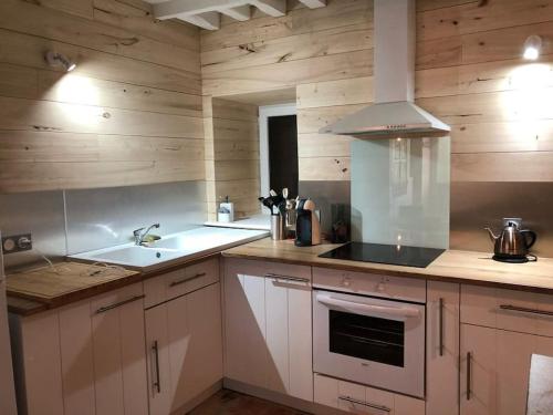 une cuisine avec des armoires blanches et un four à plaques de cuisson dans l'établissement La Petite Maison, à Saulieu