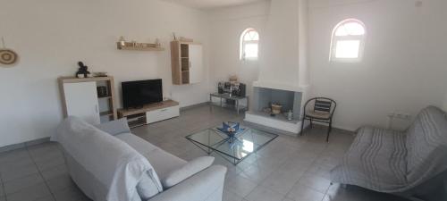 a living room with a couch and a tv at CAMARES HOUSE in Áyioi Apóstoloi