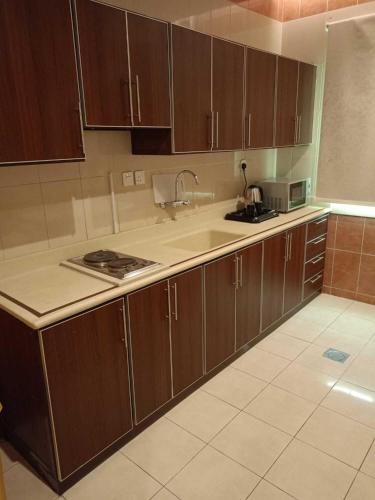 a kitchen with wooden cabinets and a counter top at Etlalat Obhur in Jeddah