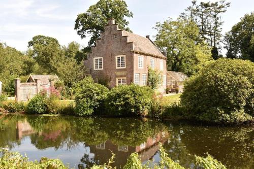 an old house reflected in the water of a lake at De Orangerie in Loenen