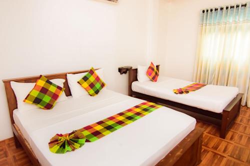 a room with two beds with colorful pillows at Sholay Villa in Galle