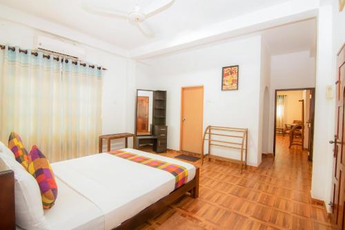 a bedroom with a white bed and a wooden floor at Sholay Villa in Galle