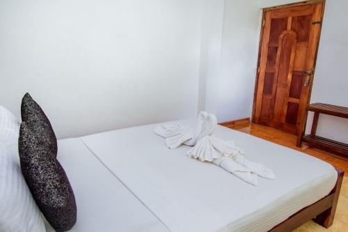 a bed with black and white pillows on it at Sholay Villa in Galle