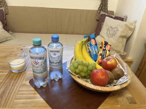 a table with a bowl of fruit and two bottles of water at Reni's 4 Sterne Ferienwohnung in Leverkusen