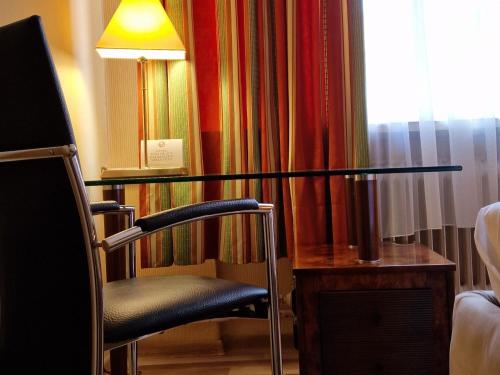 a glass table with a chair and a lamp in a room at Pension Pale' Bach in Bad Hersfeld
