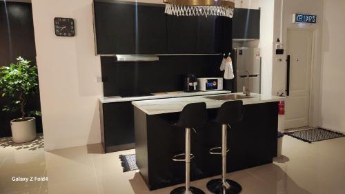 a kitchen with black cabinets and a sink and stools at Homestay Kubang Kerian by The Stay Homestay 03 in Kota Bharu