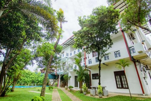 an exterior view of a white building with trees at Sholay Villa in Galle