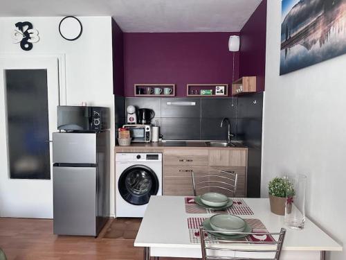 a kitchen with purple walls and a table with plates on it at Beau studio proche Strasbourg in Illkirch-Graffenstaden