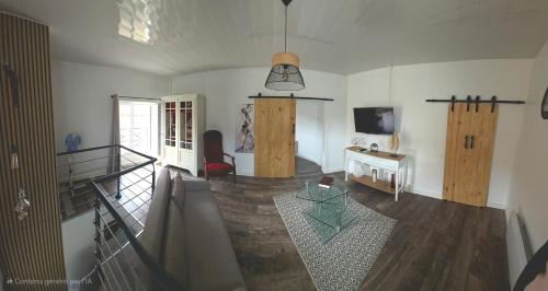 a living room with a staircase and a table and a television at Jolilina in Mirebeau