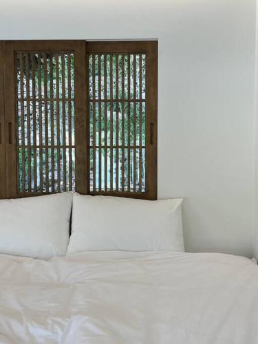a bed with white pillows in a room with windows at Stay pervade in Andong