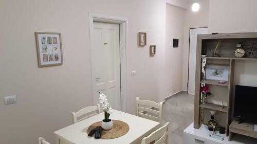 ein weißes Esszimmer mit einem Tisch und einem Fernseher in der Unterkunft ILSA Apartment in Durrës