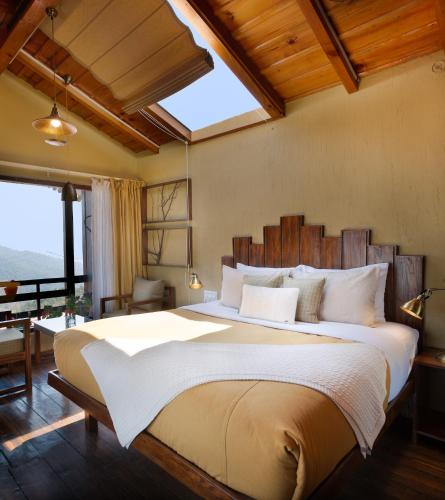 a bedroom with a large bed with a large window at The Birdcage, Mukteshwar in Mukteshwar