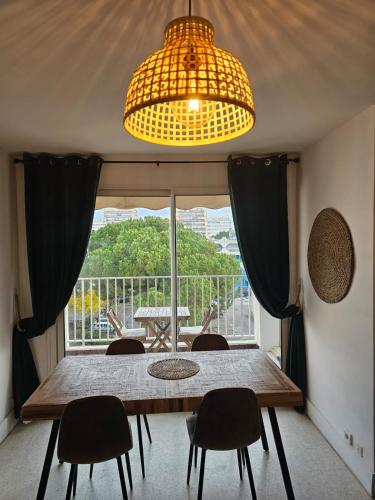une table de salle à manger avec des chaises et une grande fenêtre dans l'établissement beau t2 proche plage et commerces, logia, à La Grande Motte
