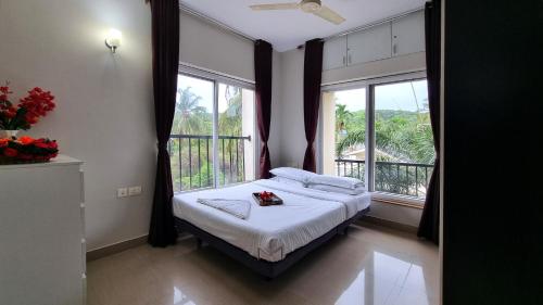 バガにあるGoa Chillout Apartment - 2BHK Baga JAQK Holidaysのベッドと2つの窓がある寝室