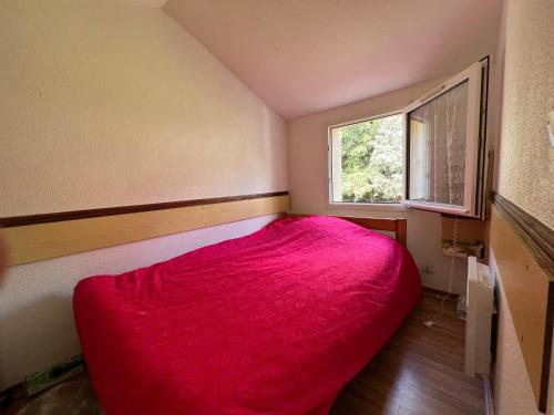 - une petite chambre avec un lit rouge et une fenêtre dans l'établissement Maison Familiale bord de mer, à Meschers-sur-Gironde