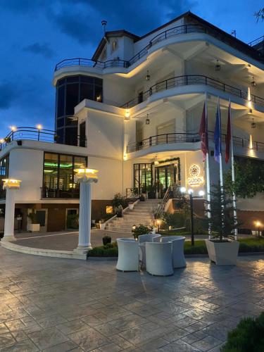 a large white building with tables in front of it at Garden Boutique Hotel in Elbasan