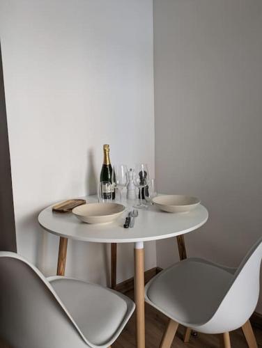 une table blanche avec deux chaises et une bouteille de vin dans l'établissement Appartement, Amour & Spa, à Montpellier