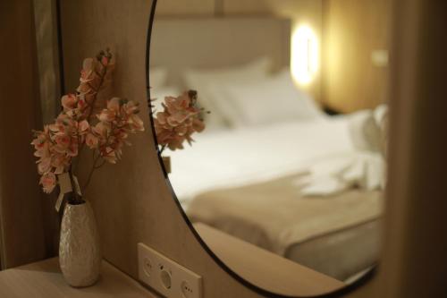 a vase with flowers on a table next to a mirror at Grand Castle Hotel in Urganch