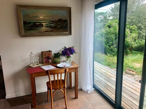 a table with a vase of flowers on it next to a window at Villa Tidinghi, plage de Rospico à pied in Névez