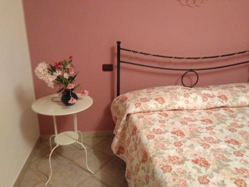 a bedroom with a bed and a table with a vase of flowers at la casa di Rosa in Selvatelle