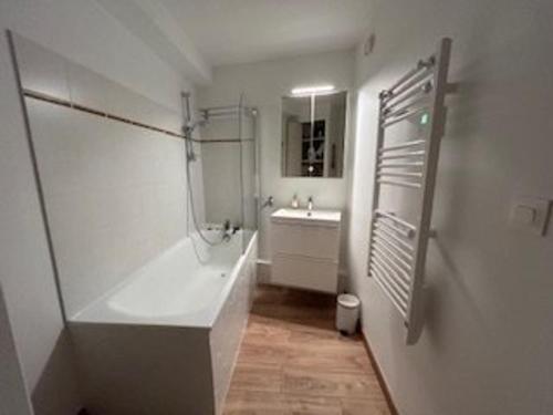 une salle de bain blanche avec une baignoire et un lavabo dans l'établissement Appartement 6 pers. avec jardinet, Chantemerle, Serre-Chevalier - FR-1-330E-37, à Saint-Chaffrey