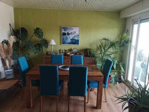 une salle à manger avec une table en bois et des chaises bleues dans l'établissement Chambre dans beau T3 très proche centre ville !, à Lorient